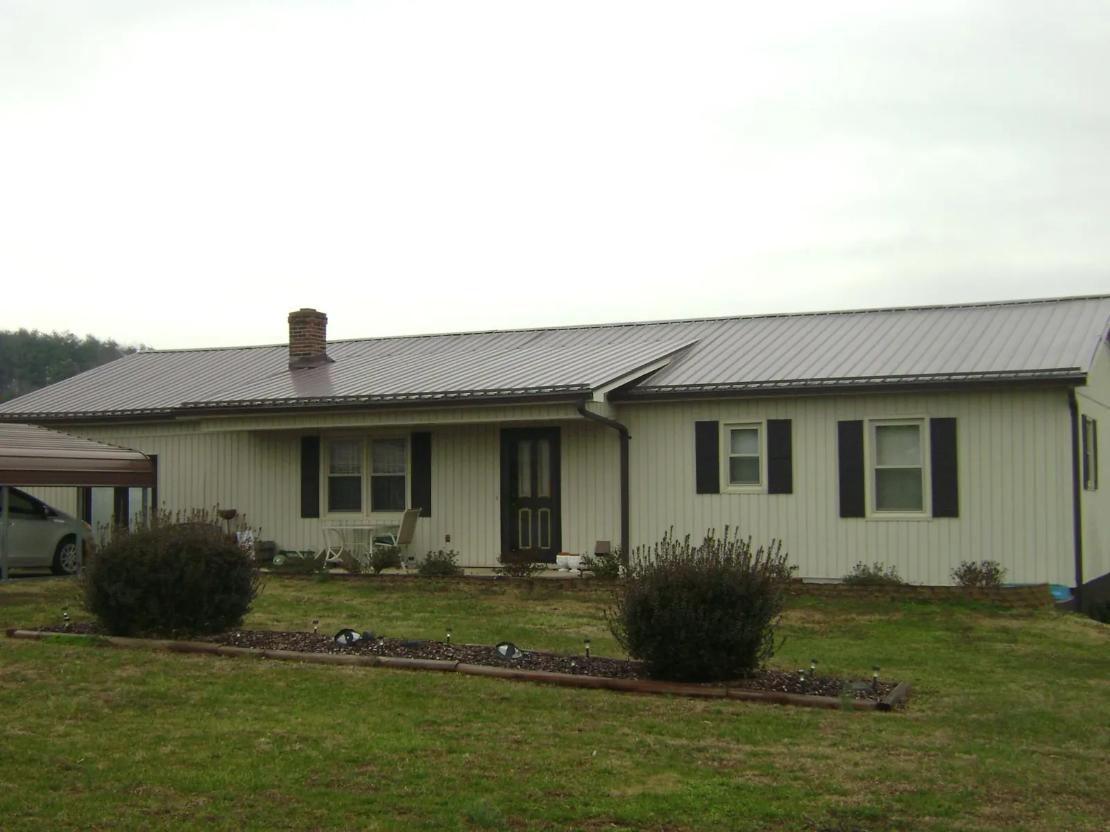 Brown metal roof on a cream sided ranch home with a brick chimney in Waynesboro