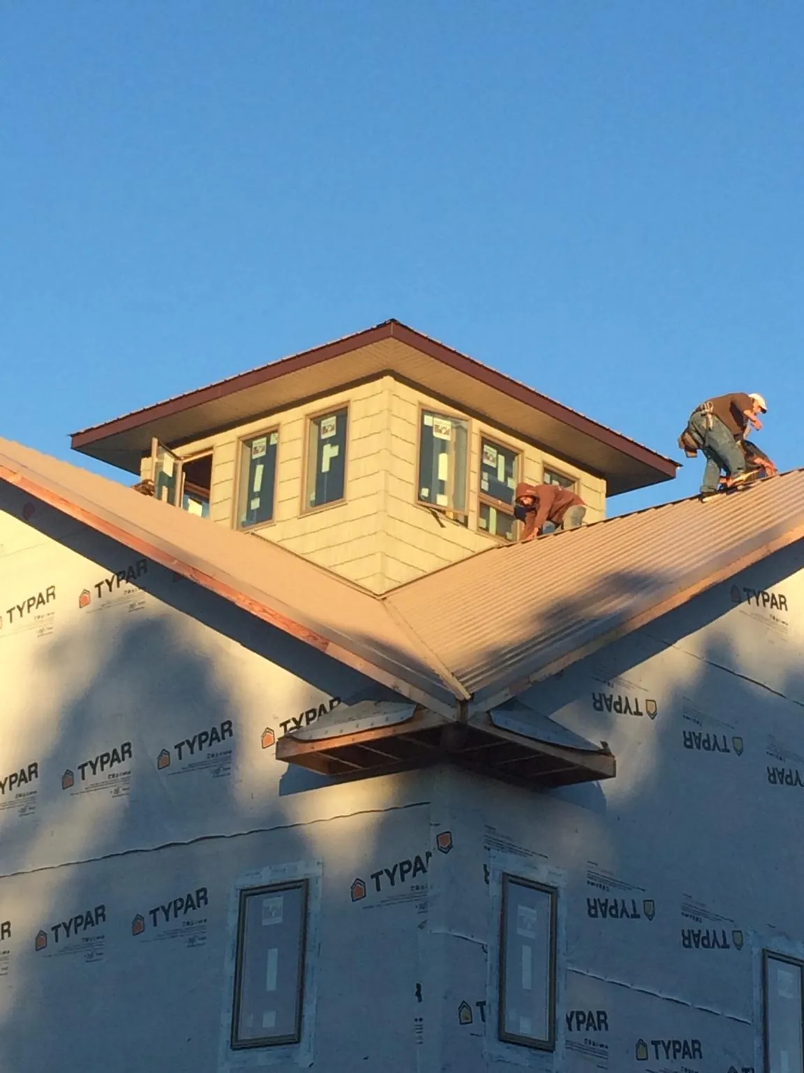 Roofers working around a rooftop cupola on a new metal roof at sunset — Roof Waterproofing in Waynesboro by Roofing Brothers